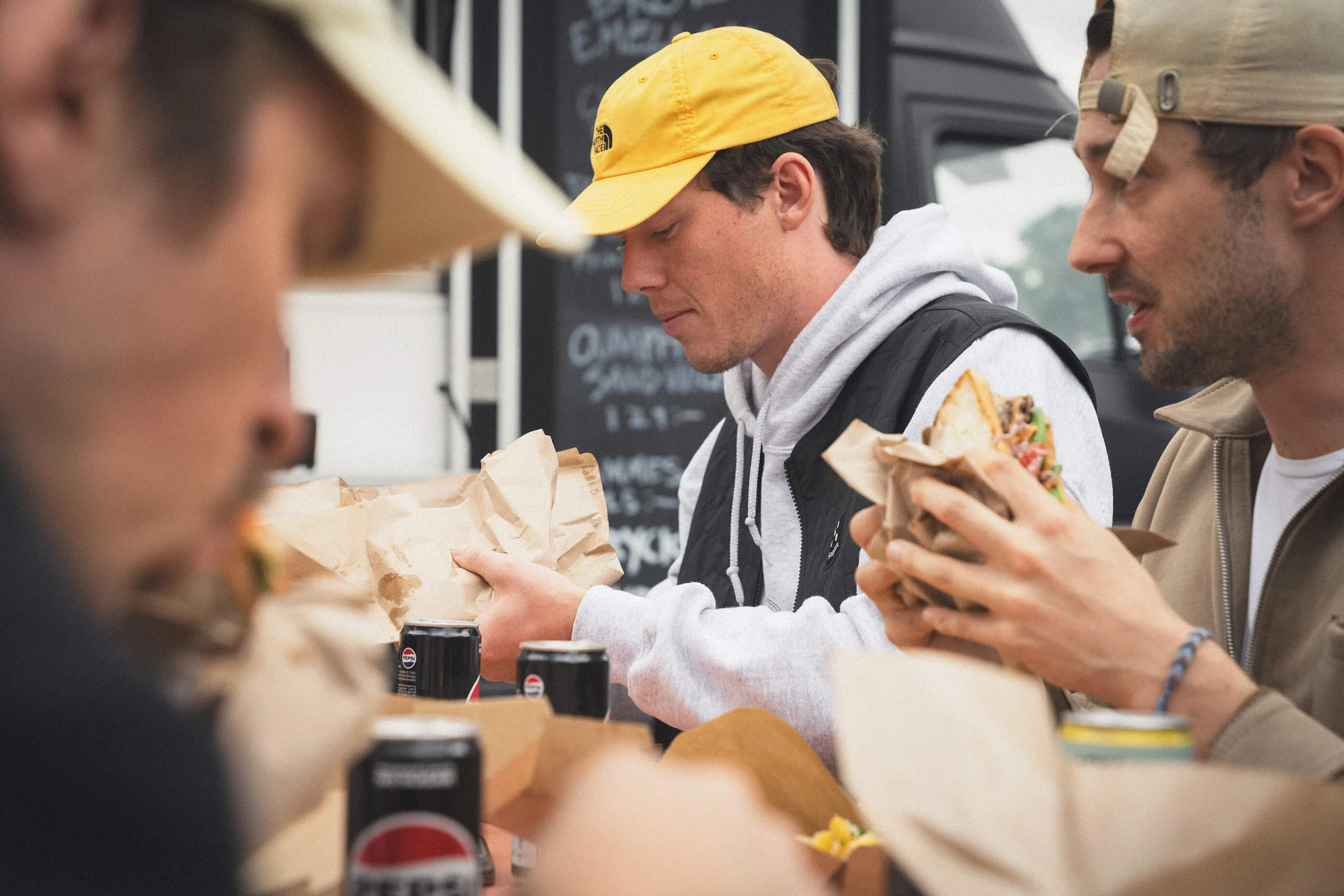 Kollegor äter mackor tillsammans vid foodtrucken under ett företagsevent