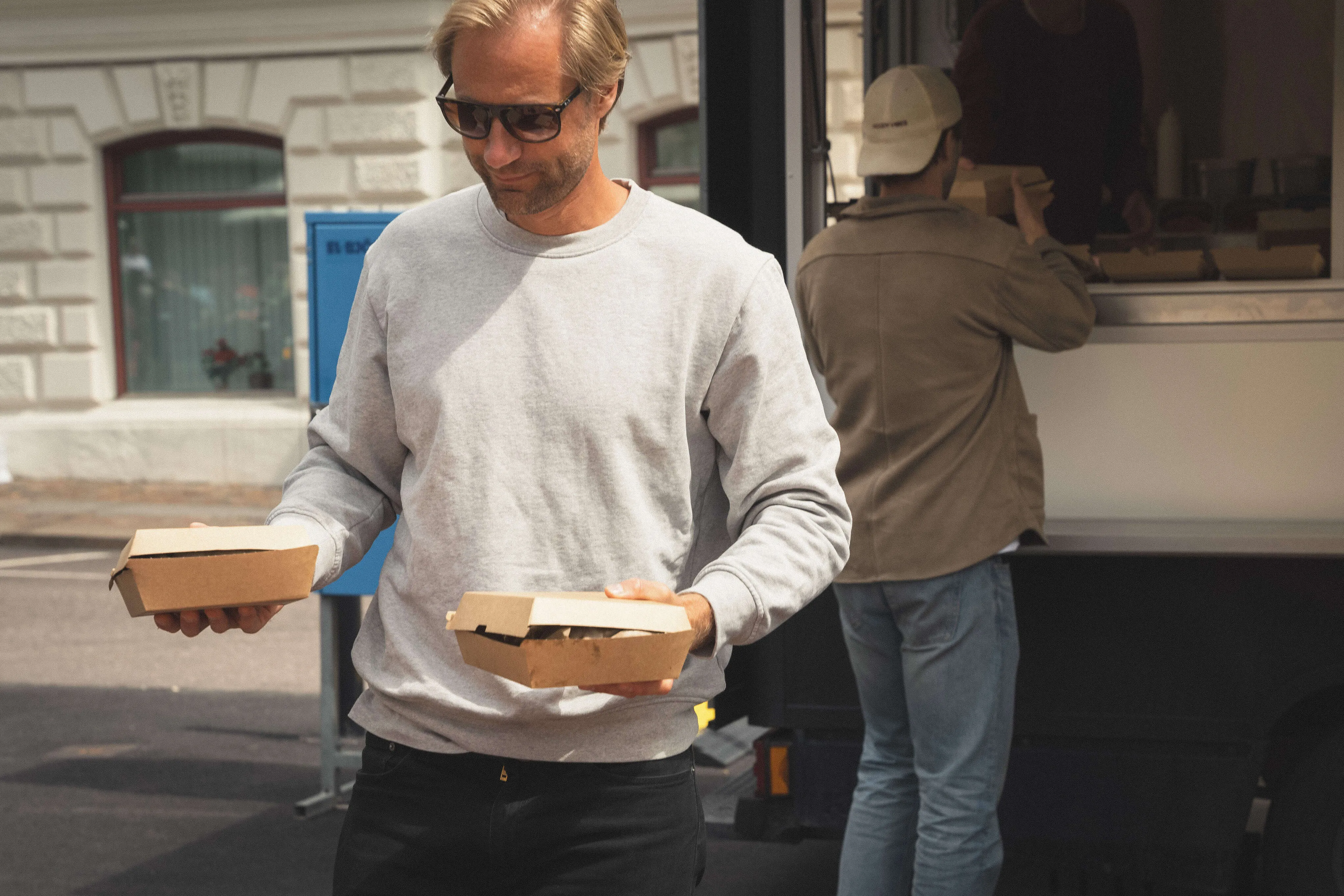 Nöjd gäst hämtar take away-boxar vid foodtruckens lucka